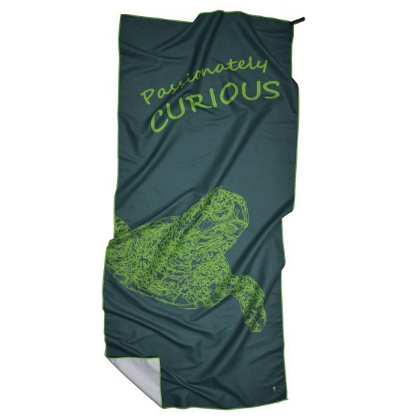 CANYLA XL Microfiber Beach Towel, curvy, green, showing text "Passionately CURIOUS", and the drawing of a turtle. Bottom left corner is folded over.